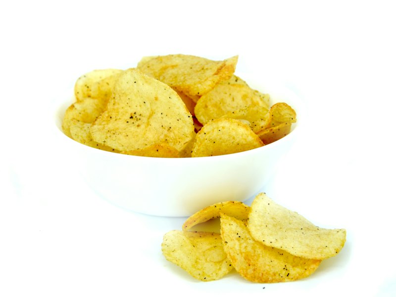 A white bowl filled with chips on top of a white table