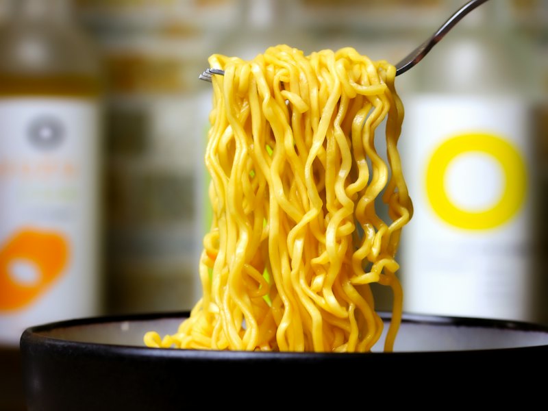 A close up of a bowl of noodles with a fork in it